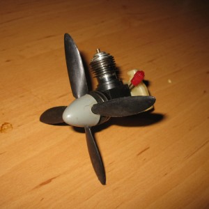 Volgens mij is dit een McCoy 0,8 cc, met vierblads prop.
Geïntegreerde tank, motor vermoedelijk afkomstig uit plastic lijnbestuurd model (geen bevestigings-ogen).
Kunststof carter, werkende veerstarter.
De vierblads prop met bijbehorende spinner is zeldzaam