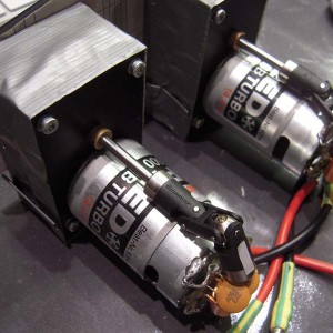 De zelfbouw reductiekasten. Er op geschroefd zitten Graupner Speed 600 BB Turbo 14.4 motoren. Net iets gunstiger voor de overspeed van de FL-8, op speedschroeben met een diameter van 42 mm/spoed 1.6. Met de 12v versie loopt het vermogen te hoog op en loopt het schip vol gas volledig uit het roer, romp half uit het water. Geen ponem! Het is immers geen S-Boot?
De kardans/kruiskoppelingen lopen prachtig onder de motoren langs...