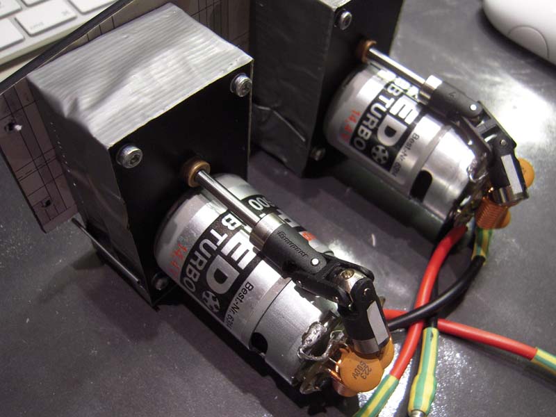 De zelfbouw reductiekasten. Er op geschroefd zitten Graupner Speed 600 BB Turbo 14.4 motoren. Net iets gunstiger voor de overspeed van de FL-8, op speedschroeben met een diameter van 42 mm/spoed 1.6. Met de 12v versie loopt het vermogen te hoog op en loopt het schip vol gas volledig uit het roer, romp half uit het water. Geen ponem! Het is immers geen S-Boot?
De kardans/kruiskoppelingen lopen prachtig onder de motoren langs...